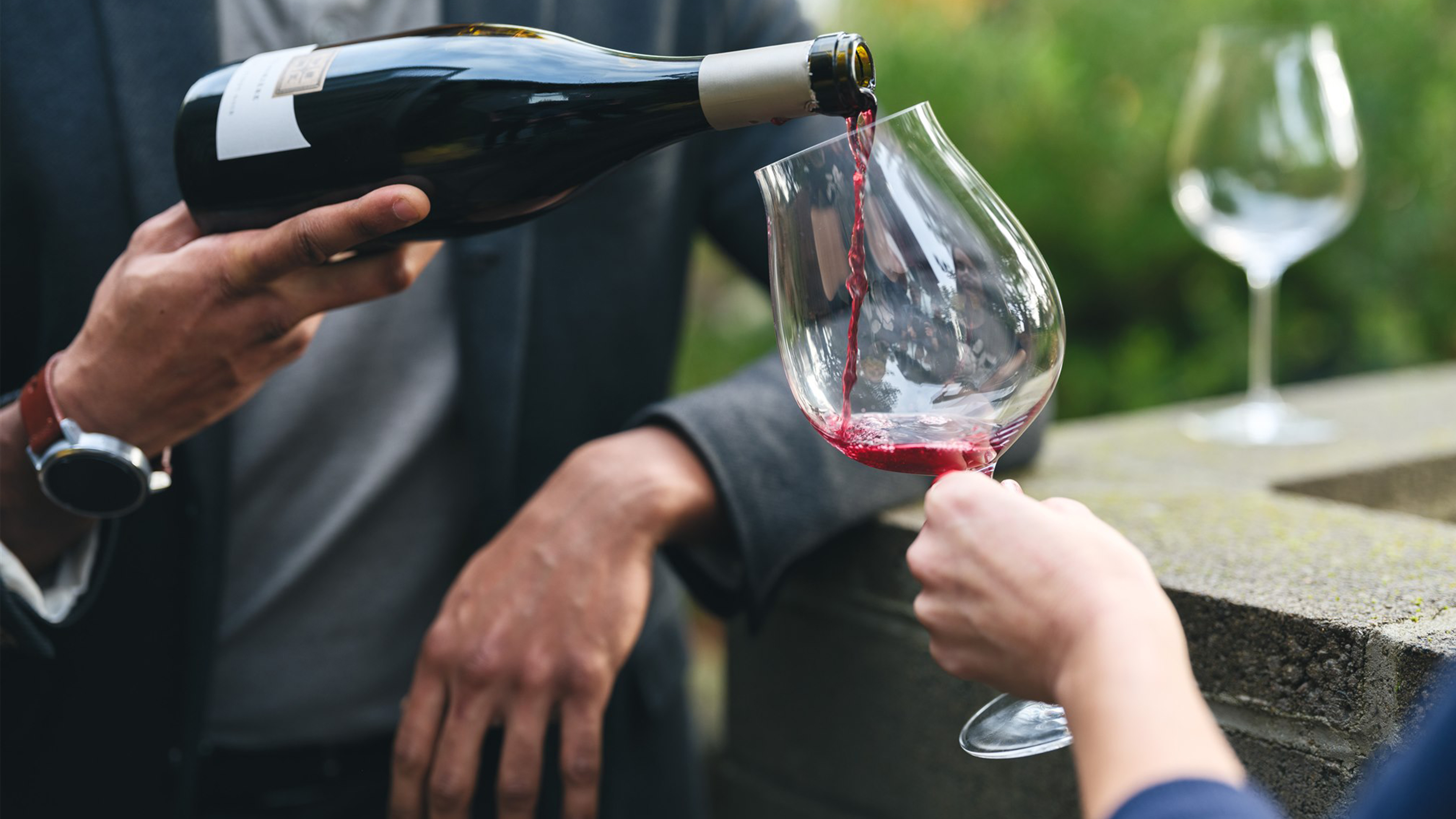 A bottle of pinot noir being poured into a glass